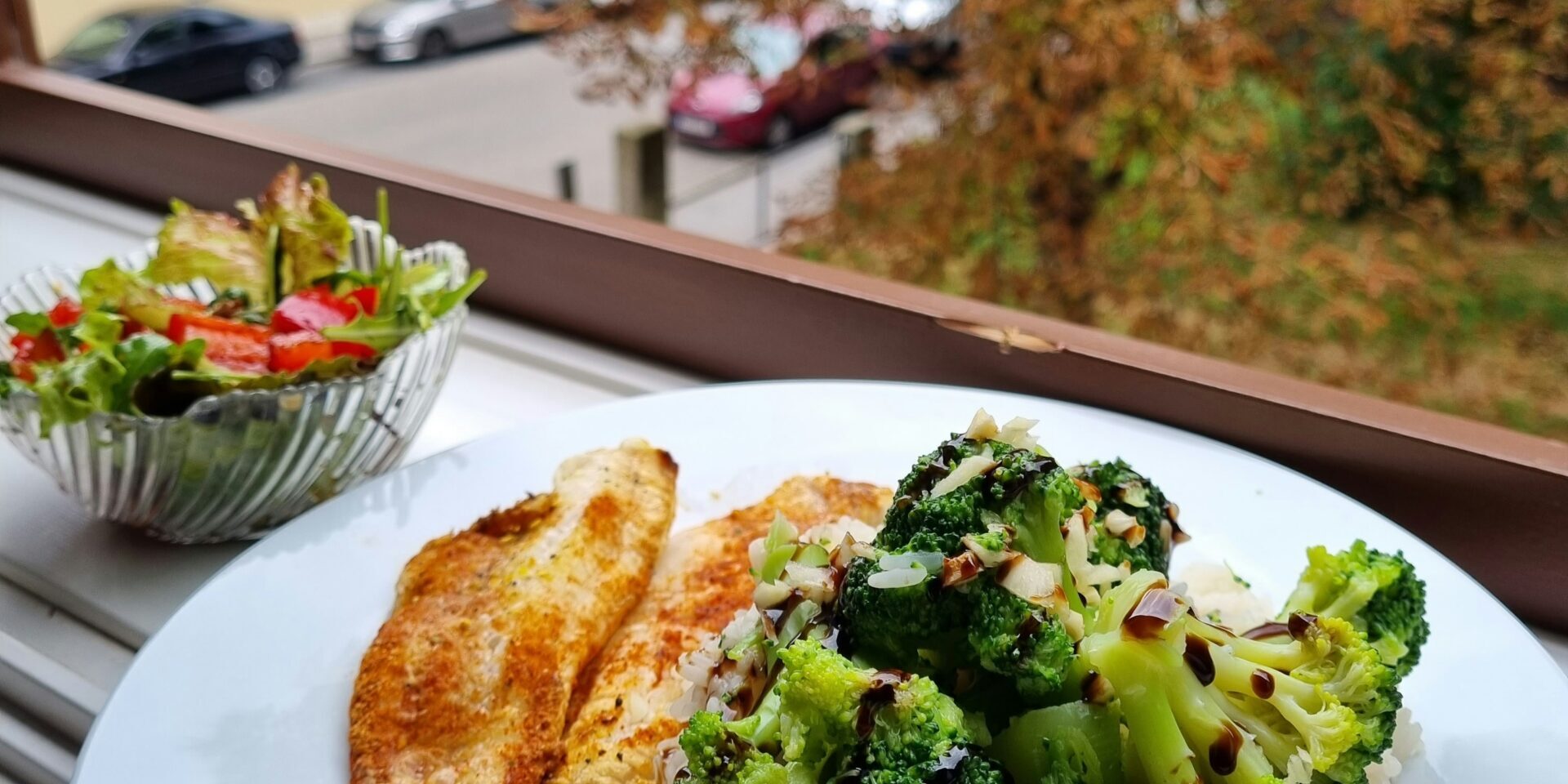a white plate topped a white plate topped with rice and broccoli next to a bowl of salad